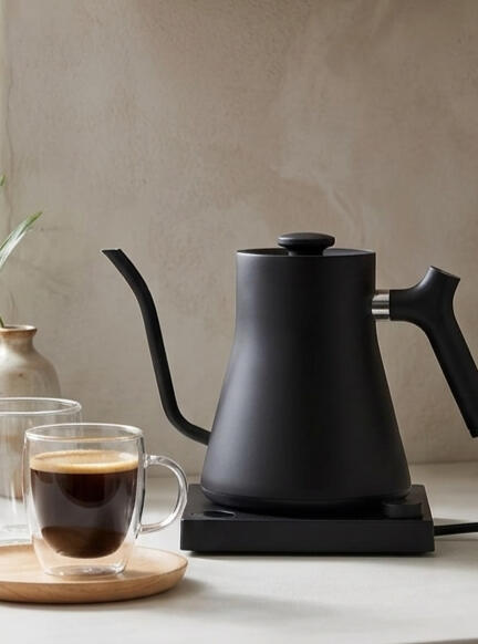 Sleek & Minimalist Kitchen Essentials Matte black gooseneck electric kettle on a modern kitchen counter with clear double-walled glass mugs nearby